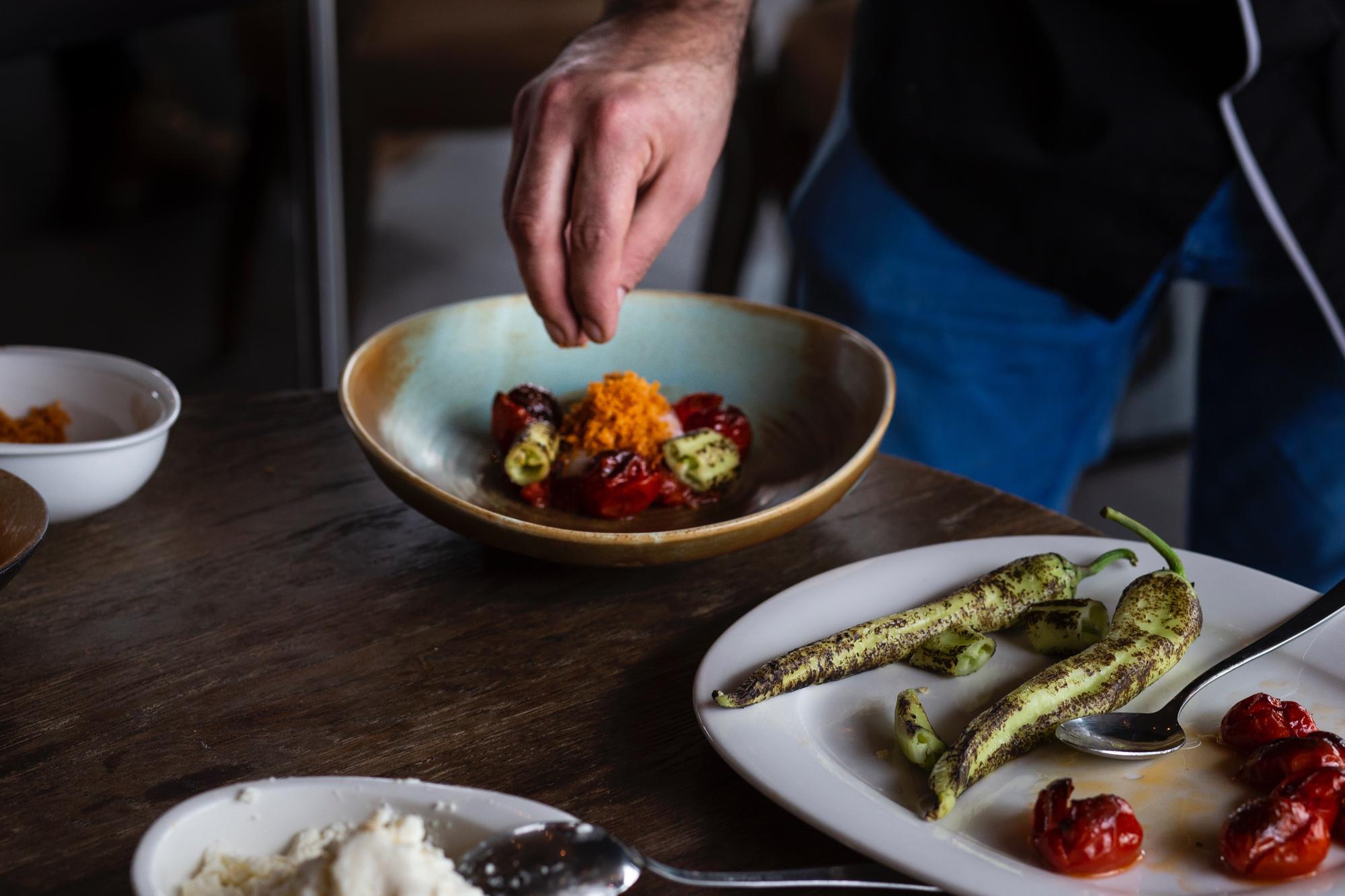 Chef arranging a simple composed plate on a wooden table